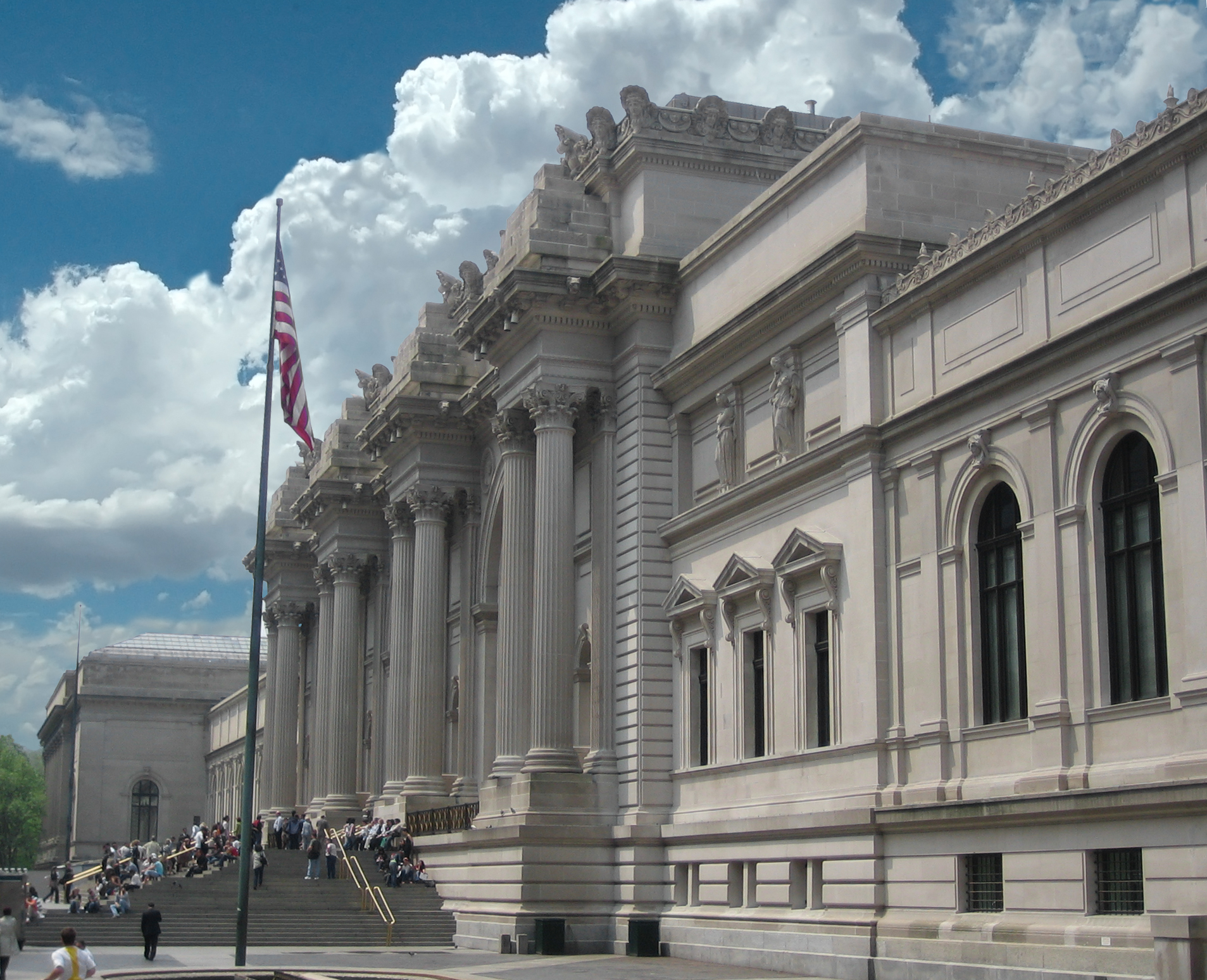 The grand entrance of the Metropolitan Museum of Art in New York City, featuring classical architecture and the American flag.