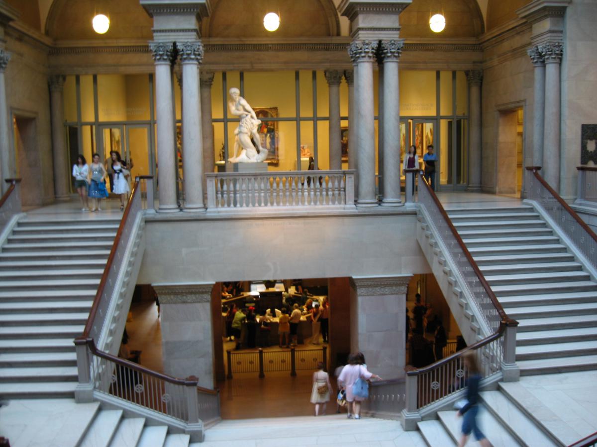 Grand staircase and interior view of the Art Institute of Chicago with classical sculptures and visitors.
