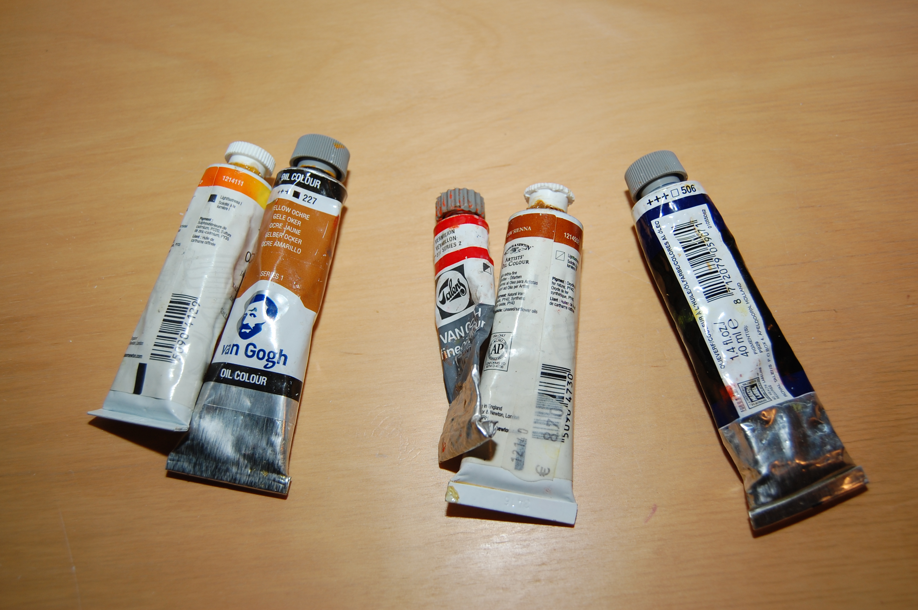 Assortment of Winsor & Newton and Van Gogh oil paint tubes on a wooden surface.
