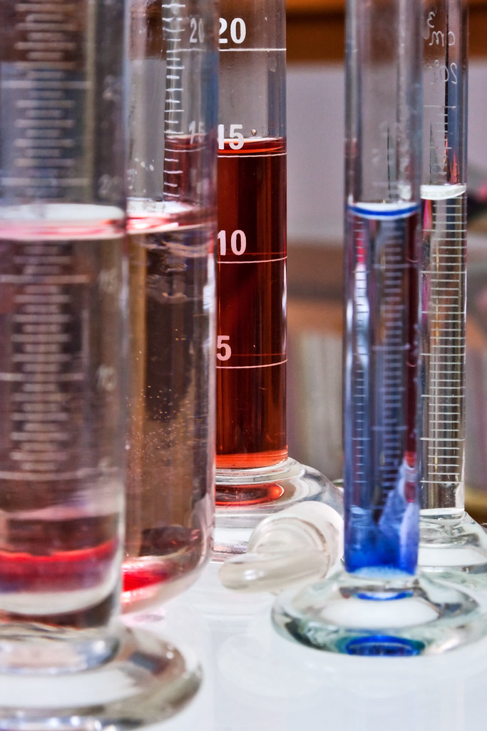 Test tubes containing paint samples used for ASTM safety testing in a chemistry lab.