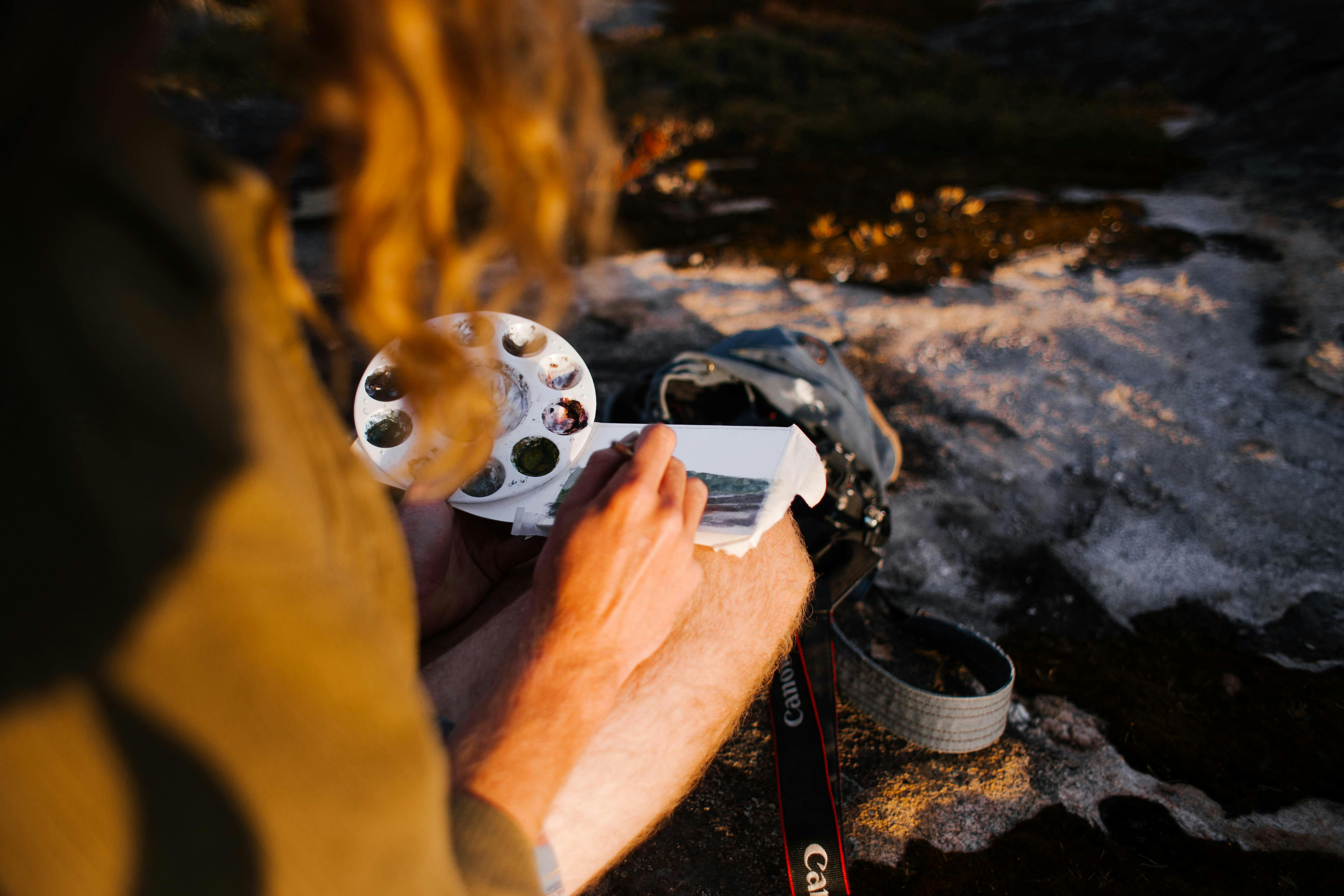 Man painting a tiny watercolor in plain-air at sunset