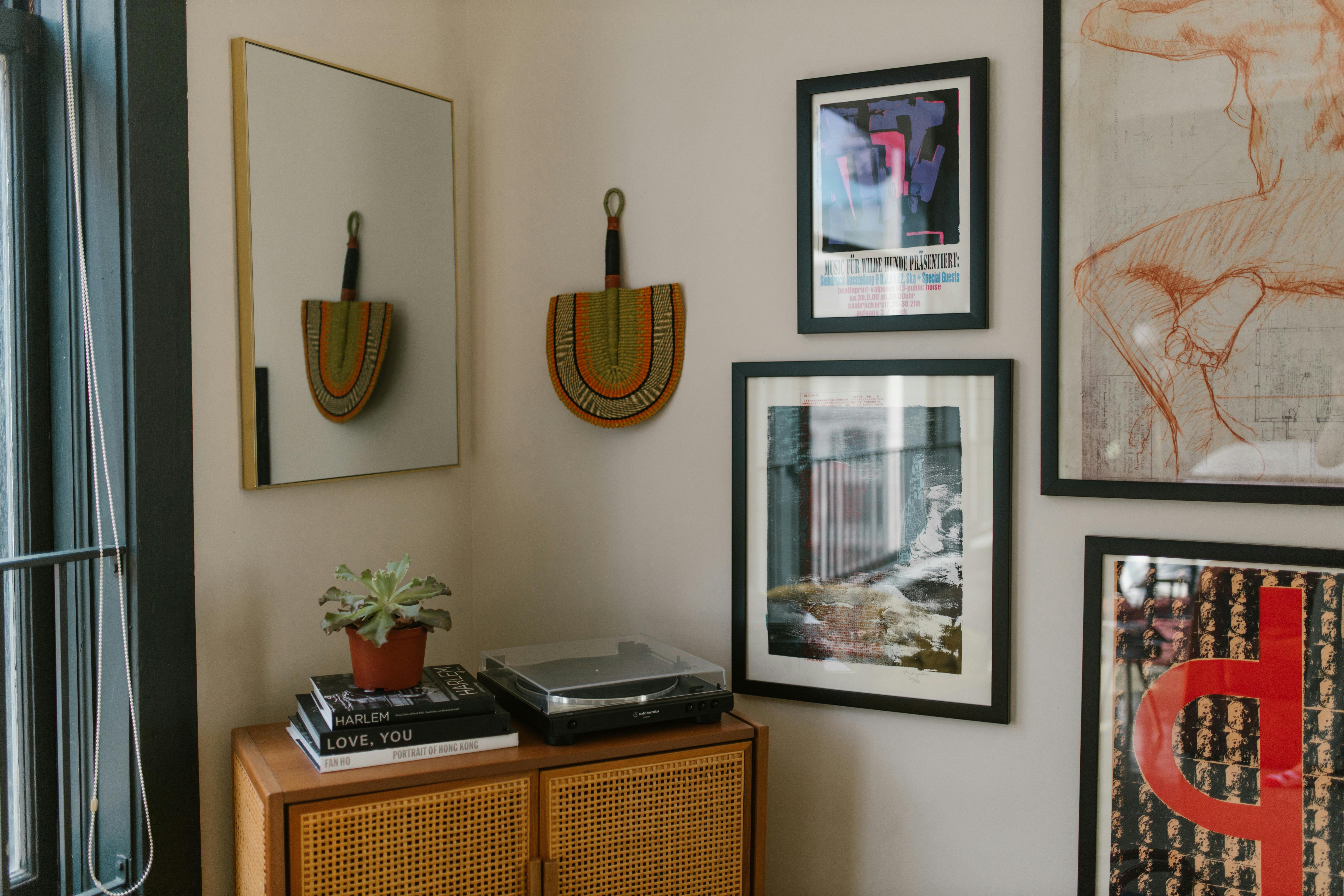 A neatly arranged gallery wall featuring framed art pieces on a white background. Beautifully showcasing framed artworks with varying styles and subjects, including posters and sketches, against a clean backdrop. Perfect example of decorating large walls with art. Picture Frames on the Wall · Free Stock Photo. photographic picture frames on wall next to window. accurate and relevant to the subject decorating-large-walls-with-art. 2019. Chriss<br>, Holland