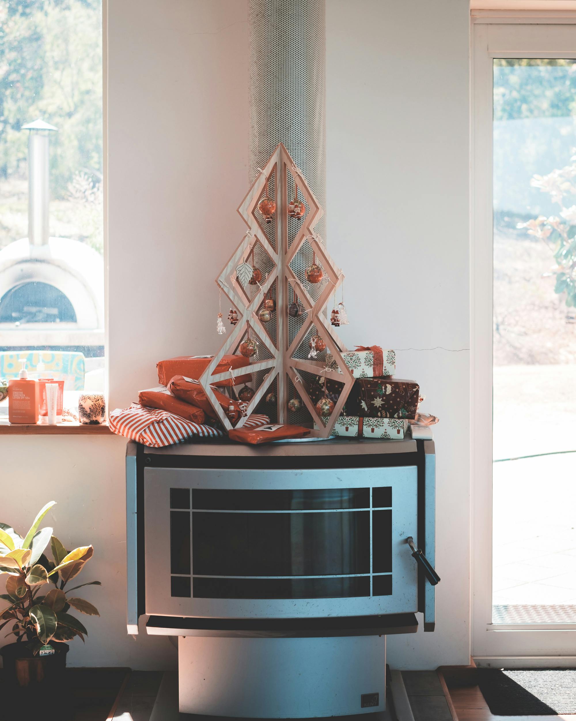 Modern fireplace decorated with a wooden Christmas tree and gifts