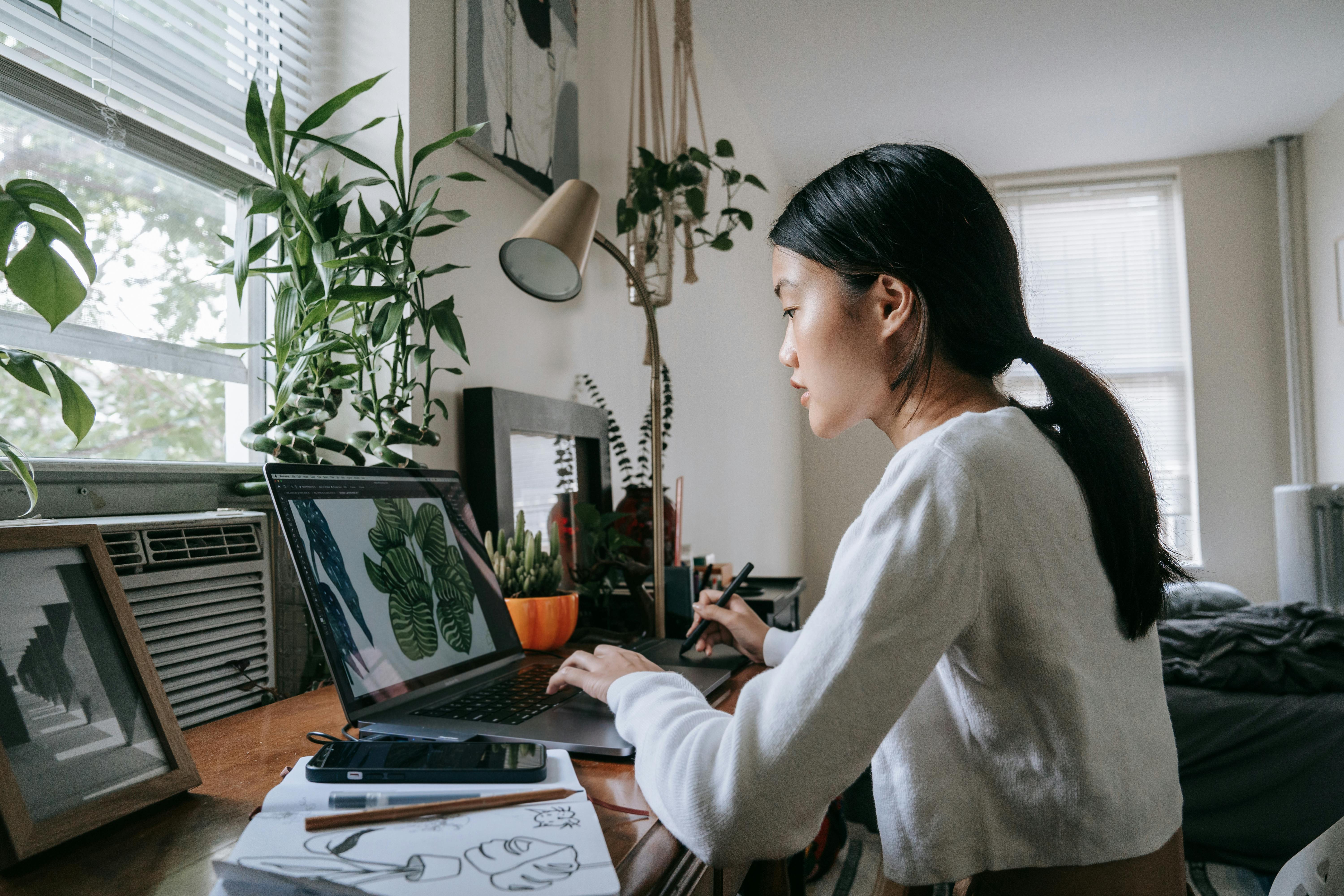 Woman using laptop to work on digital sketch art with creative tools.