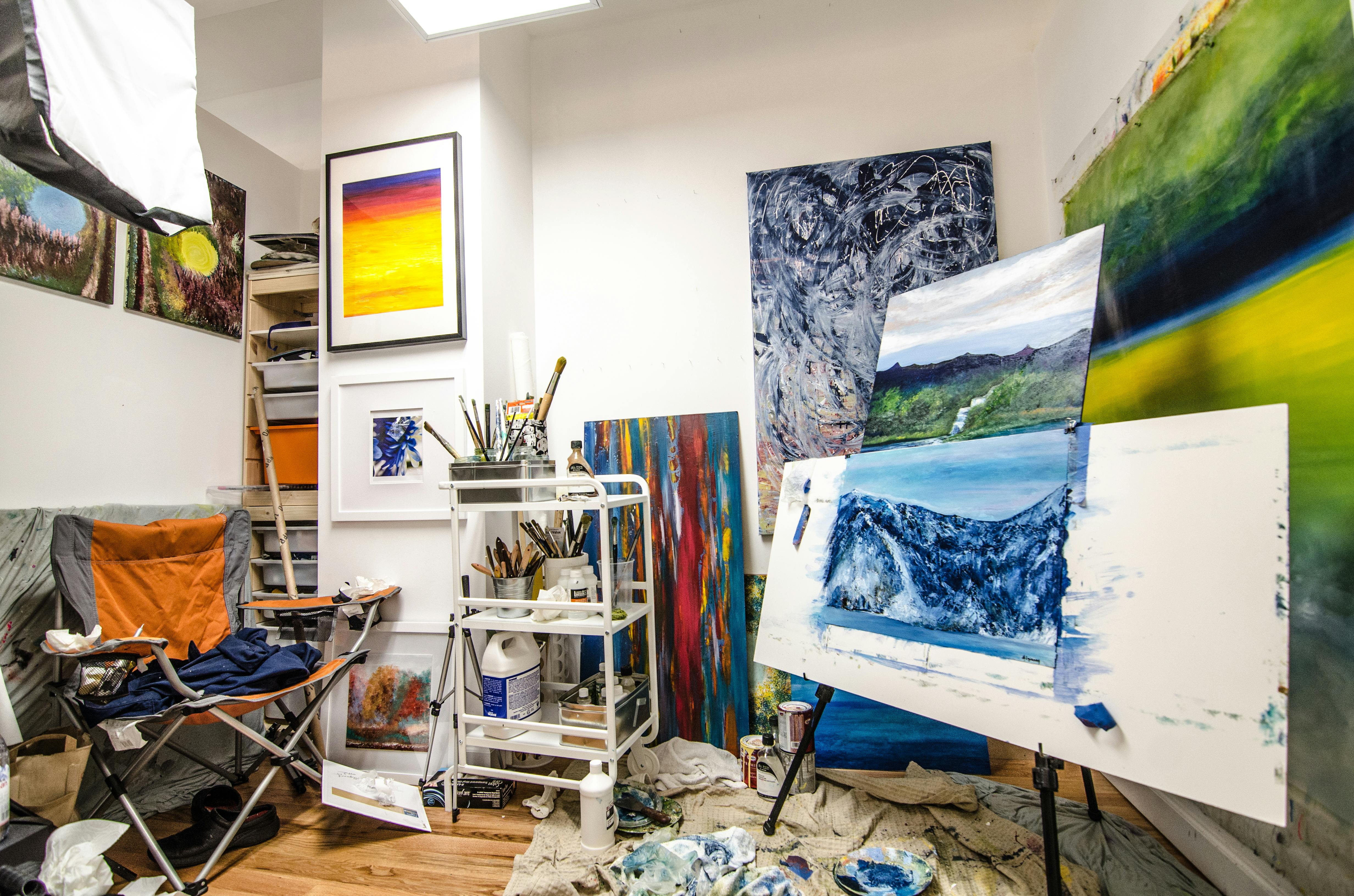 Creative artist studio workspace with paintings in progress, paintbrushes, and art supplies for budget-friendly art creation