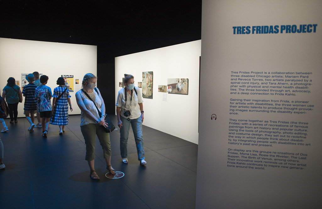 Visitors wearing masks view art at the Tres Fridas Project exhibit inspired by Frida Kahlo.