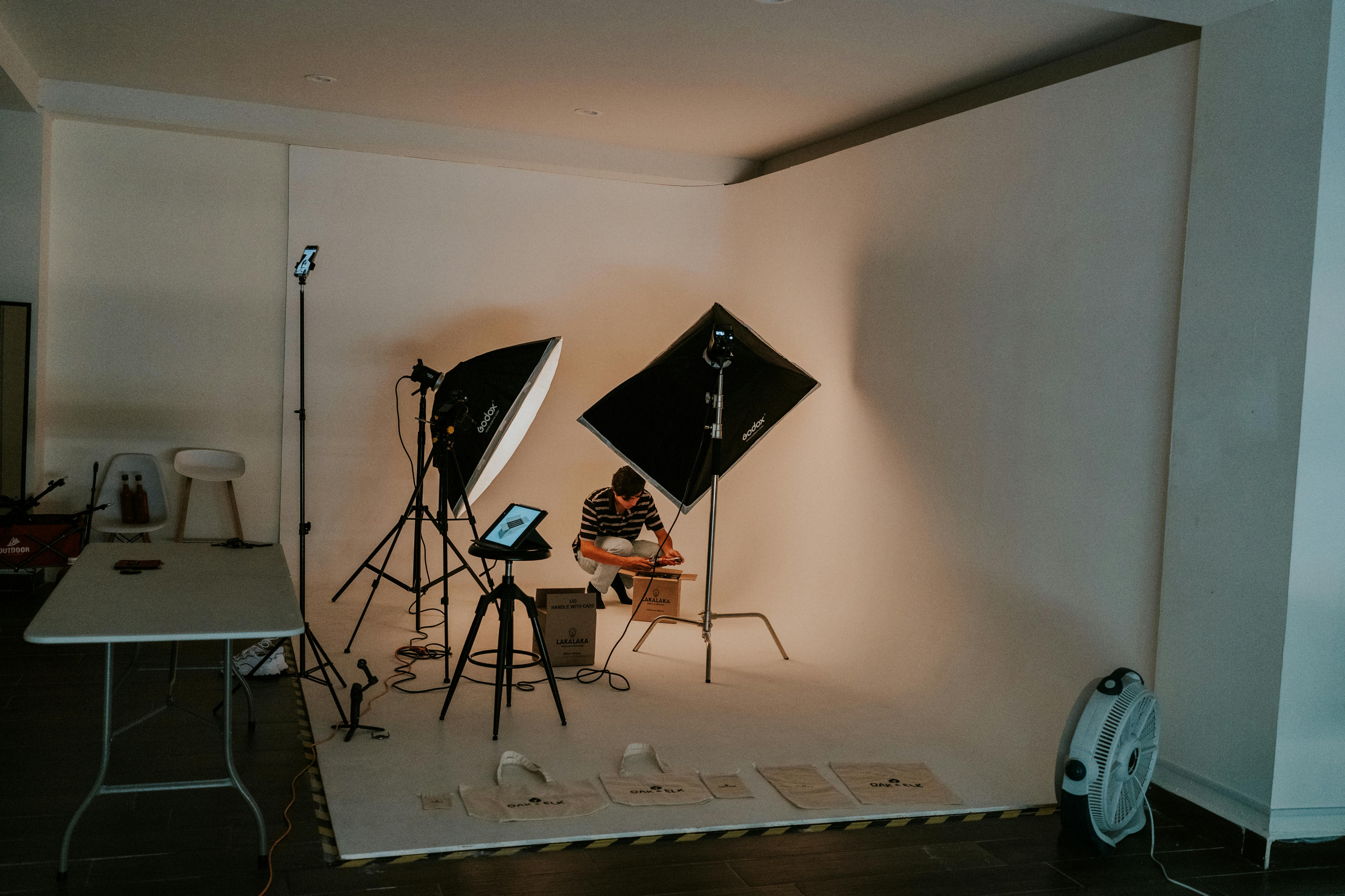 Man setting up lighting equipment in an art studio for a photo session