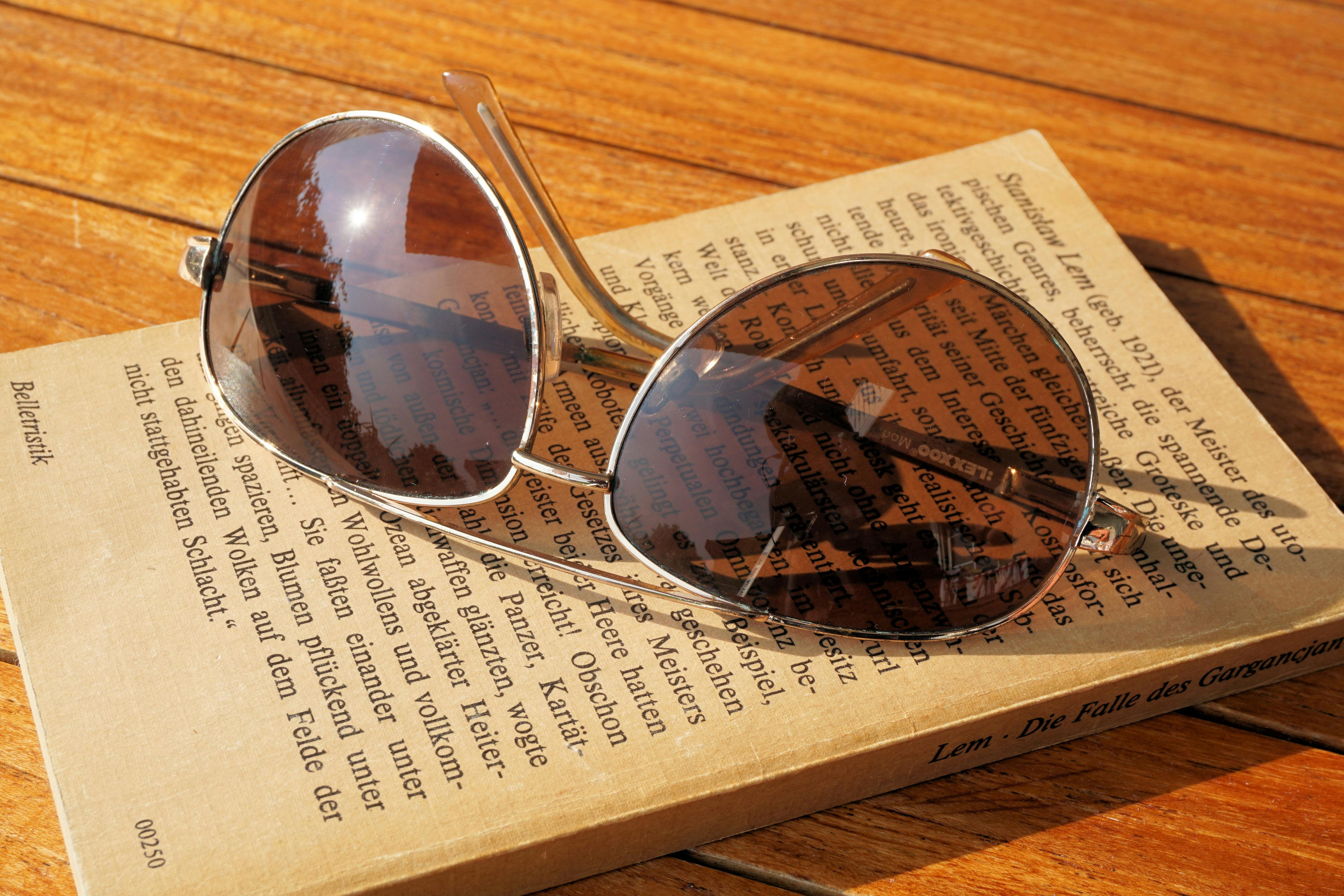 stainless steel aviator sunglasses resting on a book page showing techniques to protect paintings from light damage