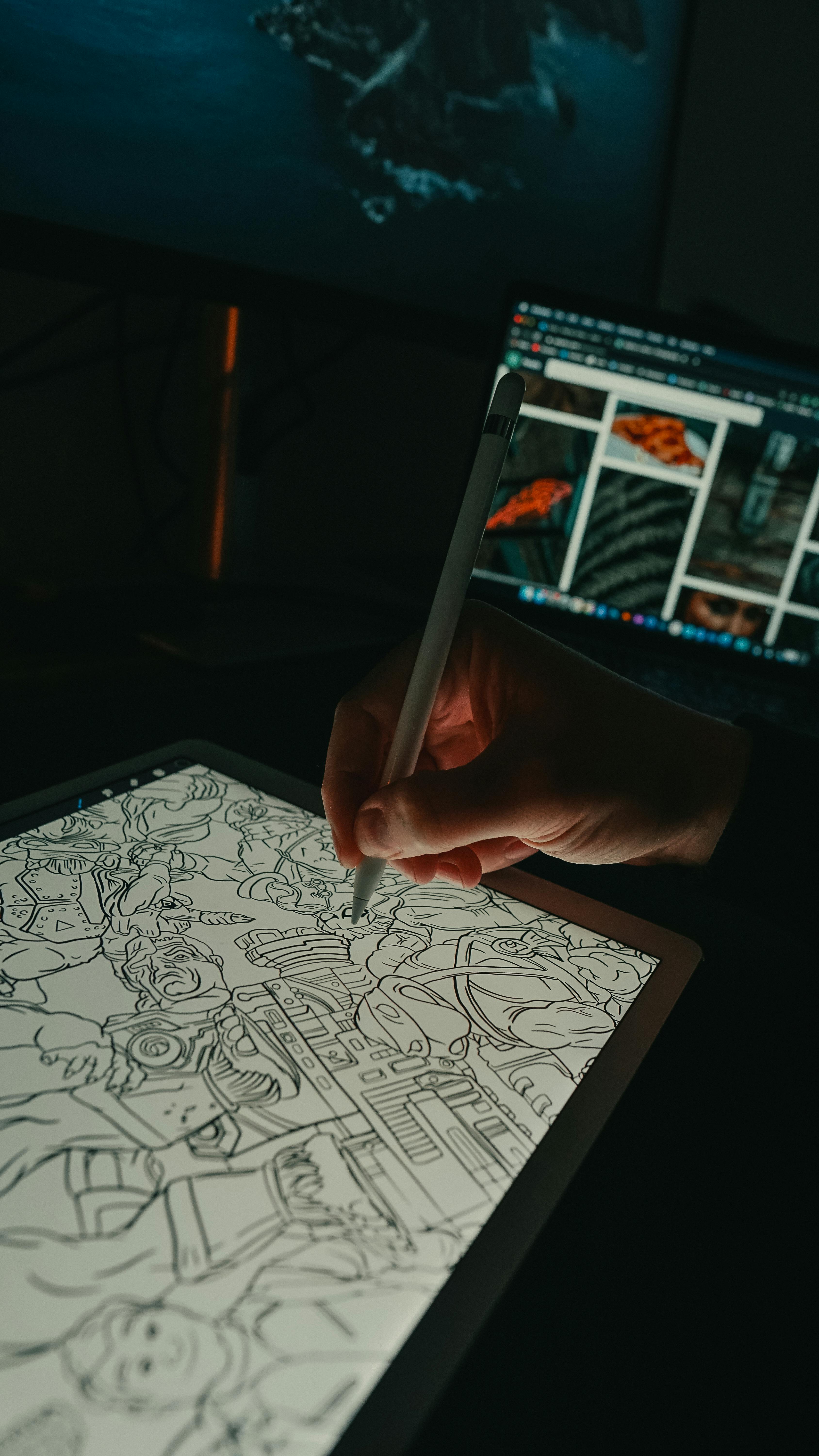 Hand using an Apple Pencil to draw on an iPad screen, with a laptop in the background displaying images.