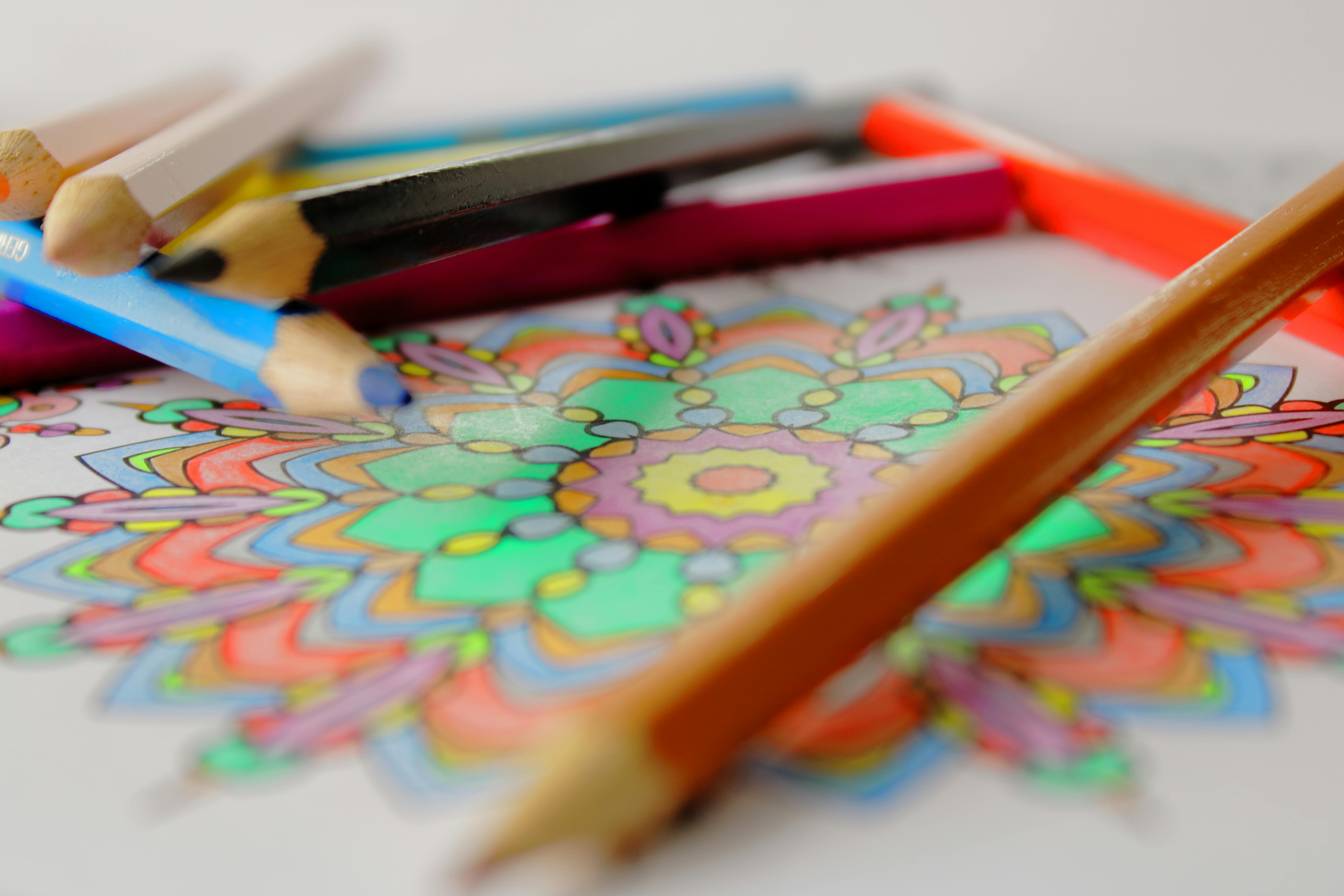 Close-up of Prismacolor Premier colored pencils scattered on a partially colored mandala-style coloring page.