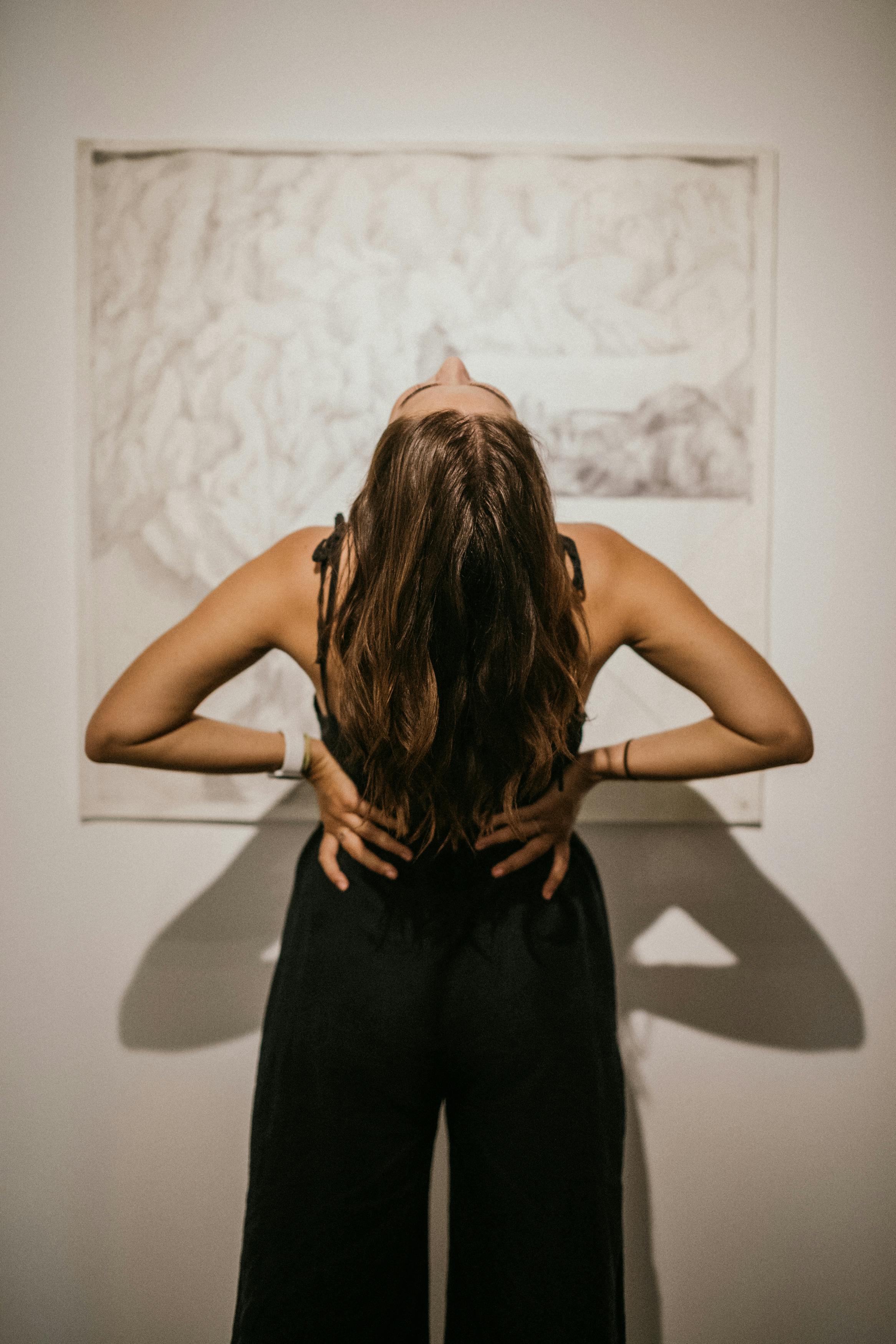 Woman in black clothes leaning back against abstract art background, confident pose, free stock photo