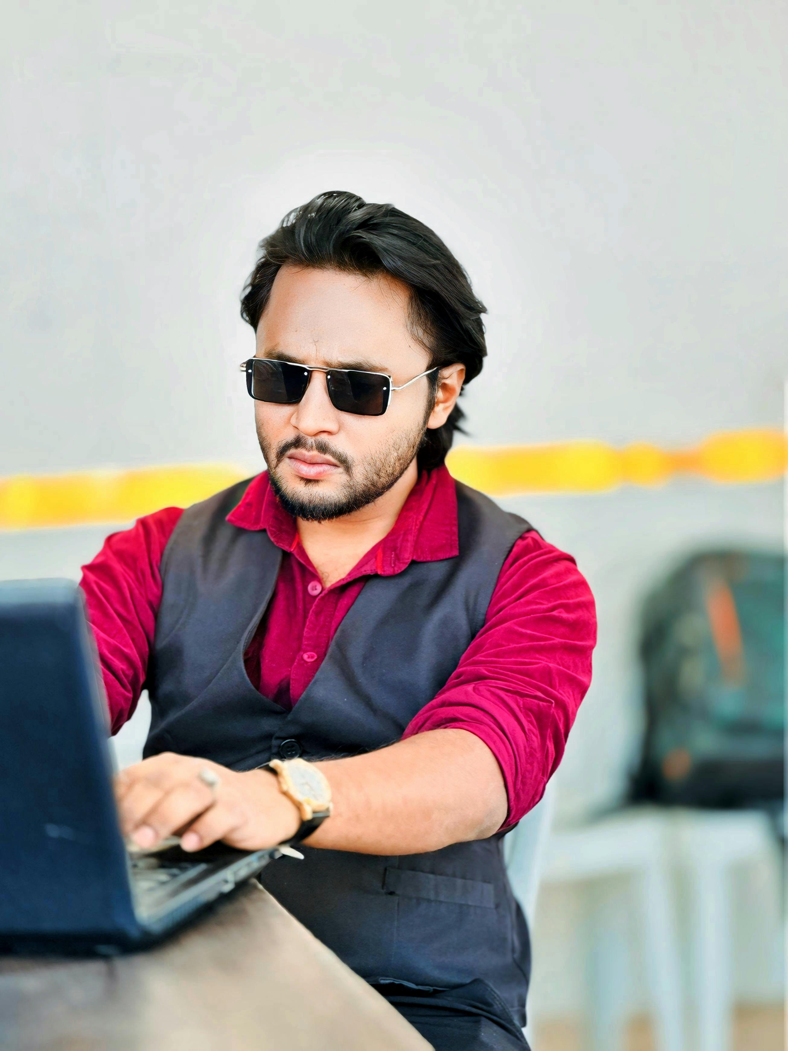 Business professional in maroon shirt using laptop for art business innovation in modern workspace