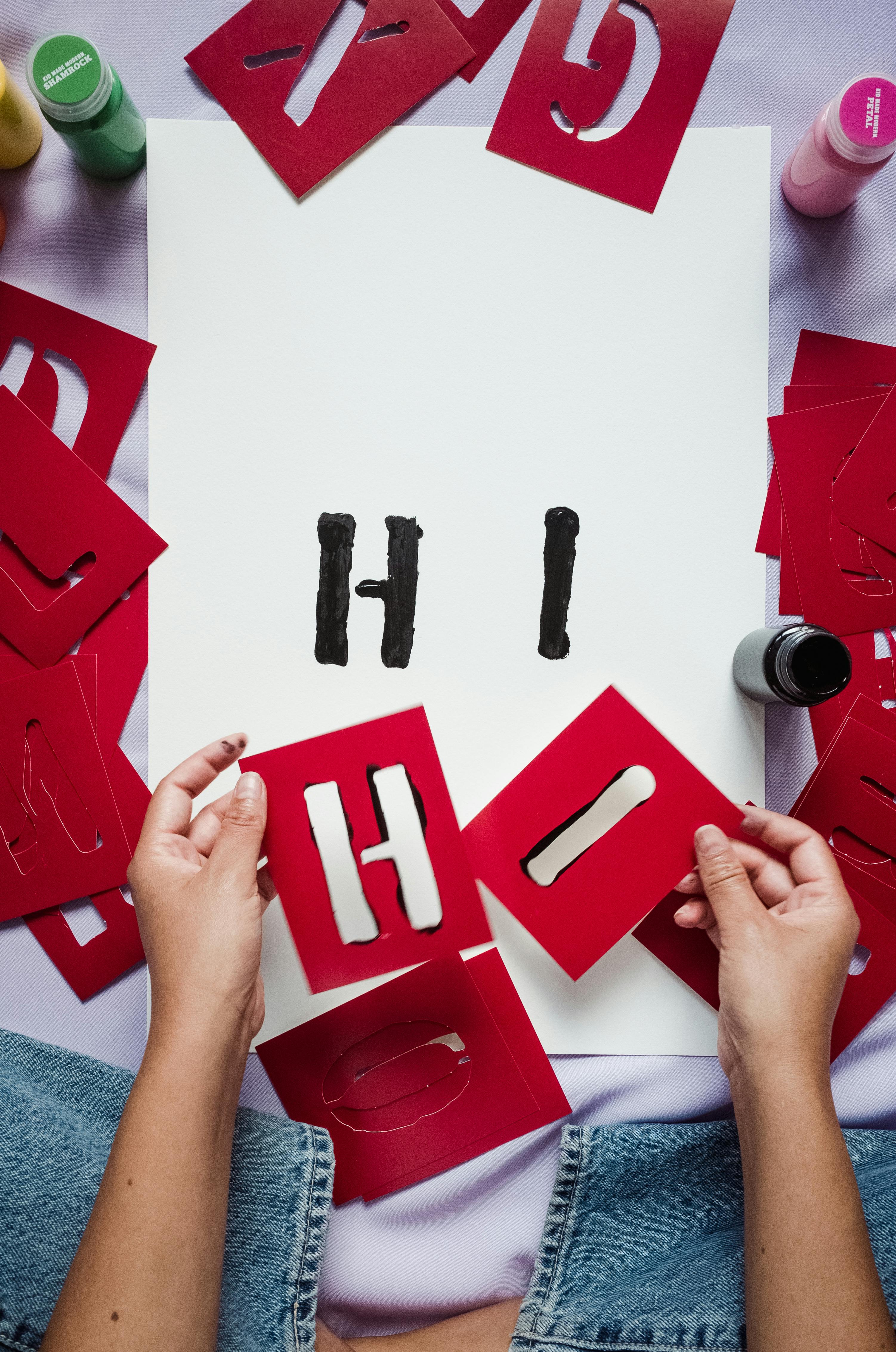 Create 'Hi' with red paper stencils on white paper – free stock photo