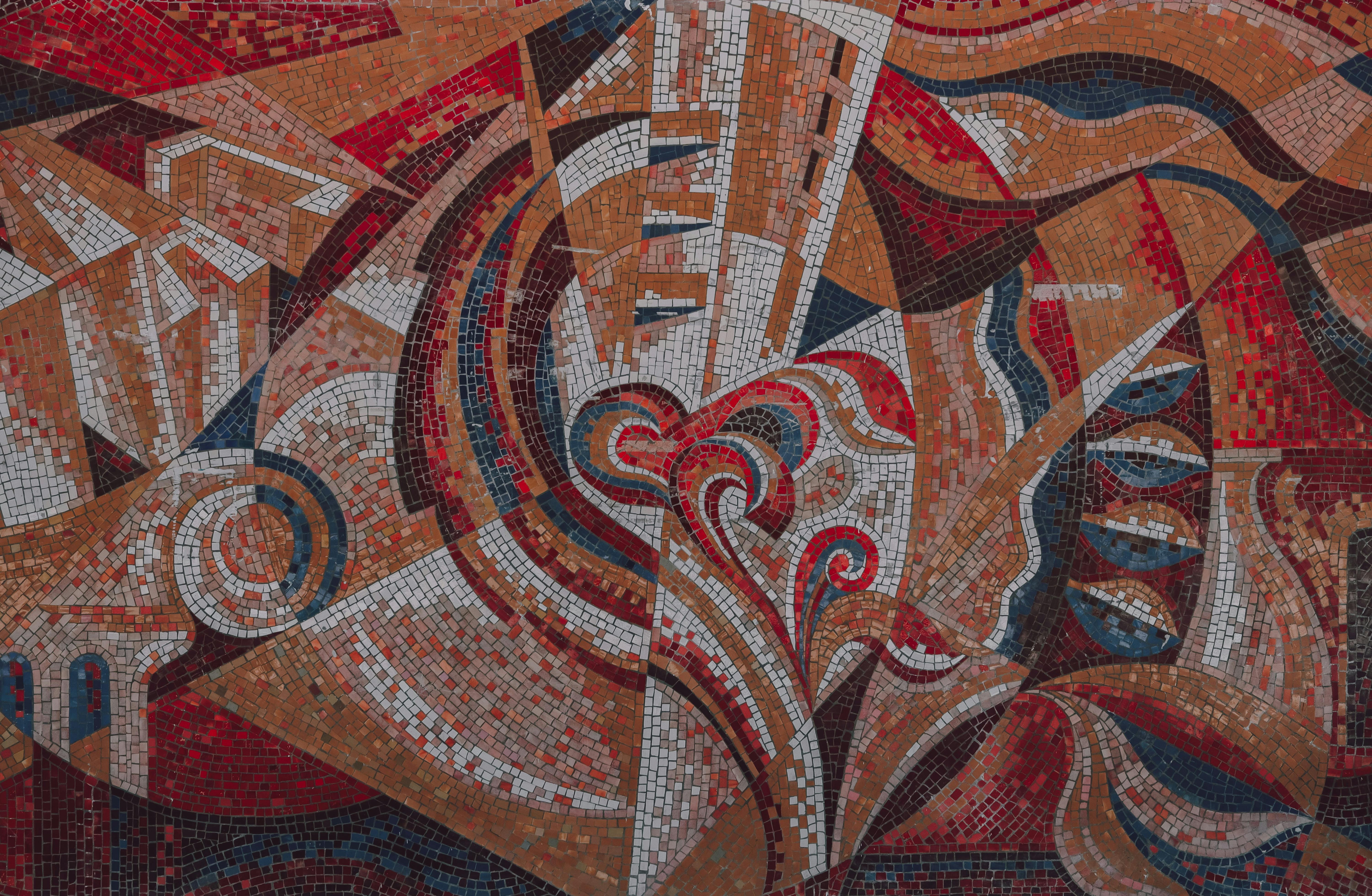 Abstract mosaic artwork with vibrant red, orange, and blue tiles forming a dynamic pattern.