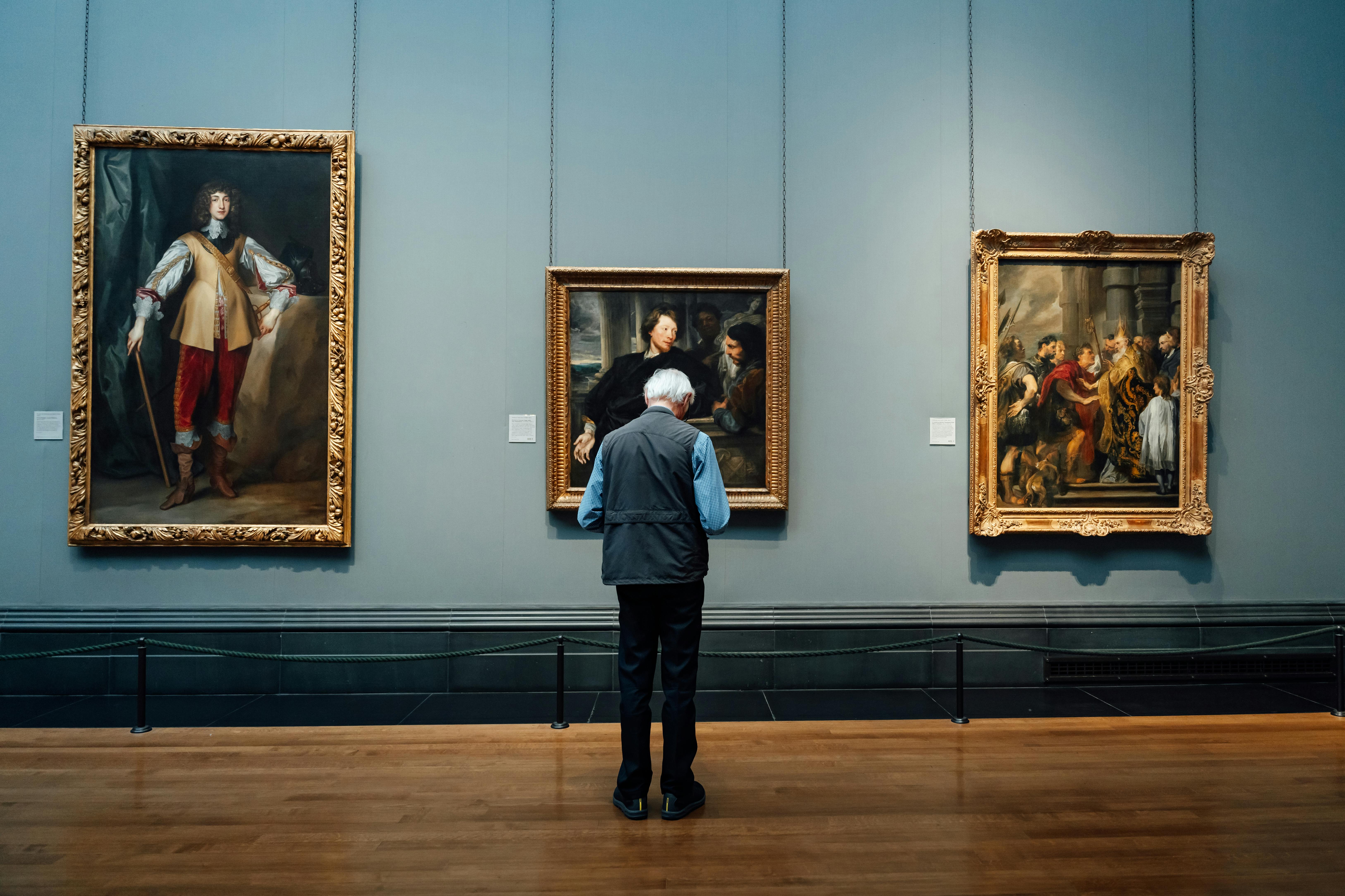 Art enthusiast observing classic paintings in a museum gallery. A detailed view of curated artworks in a gallery setting. Free art museum visit for art aficionados.