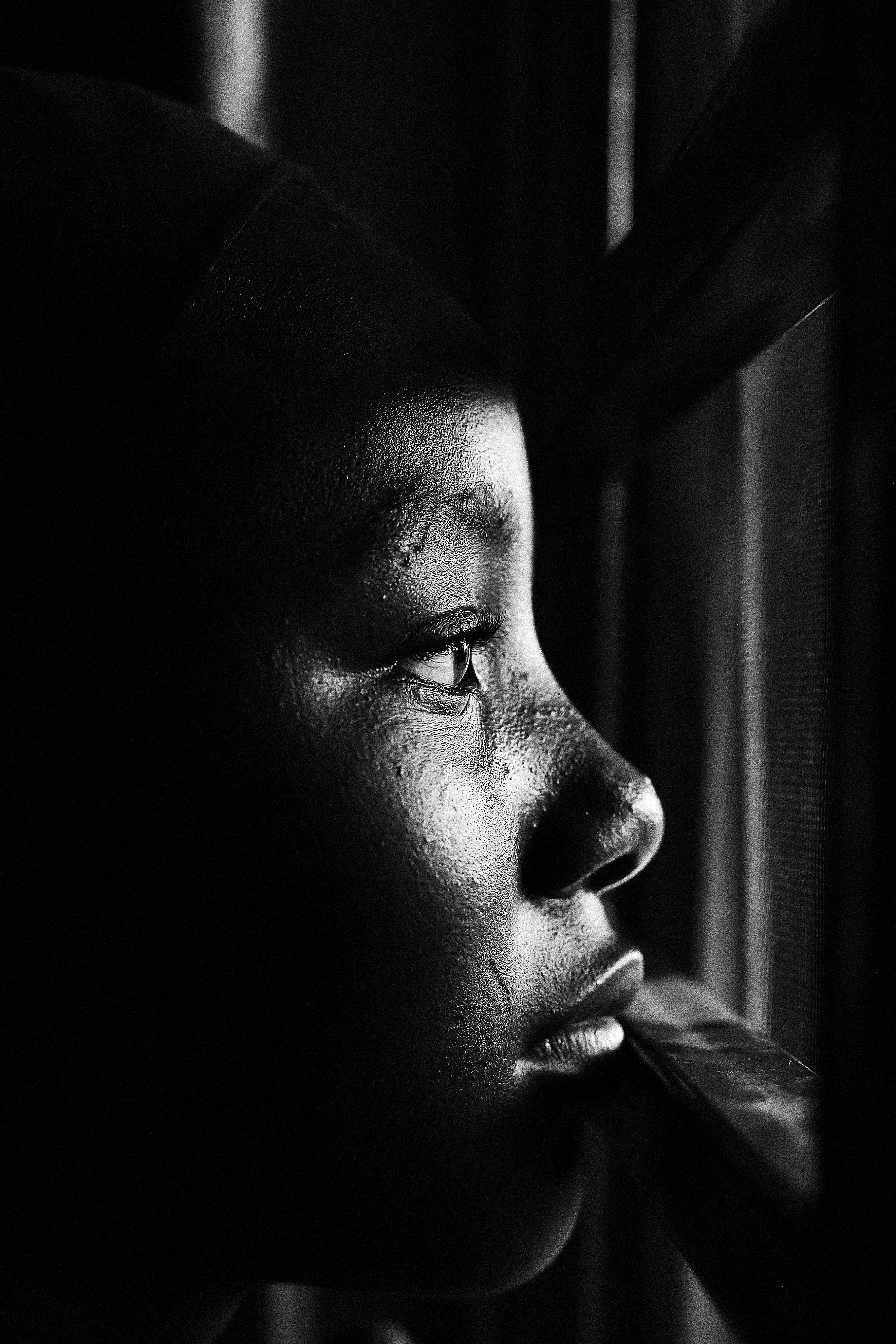 Close-up of a child's face in profile, with one side illuminated by sunlight and the other in shadow, highlighting the texture of the skin and the eye.