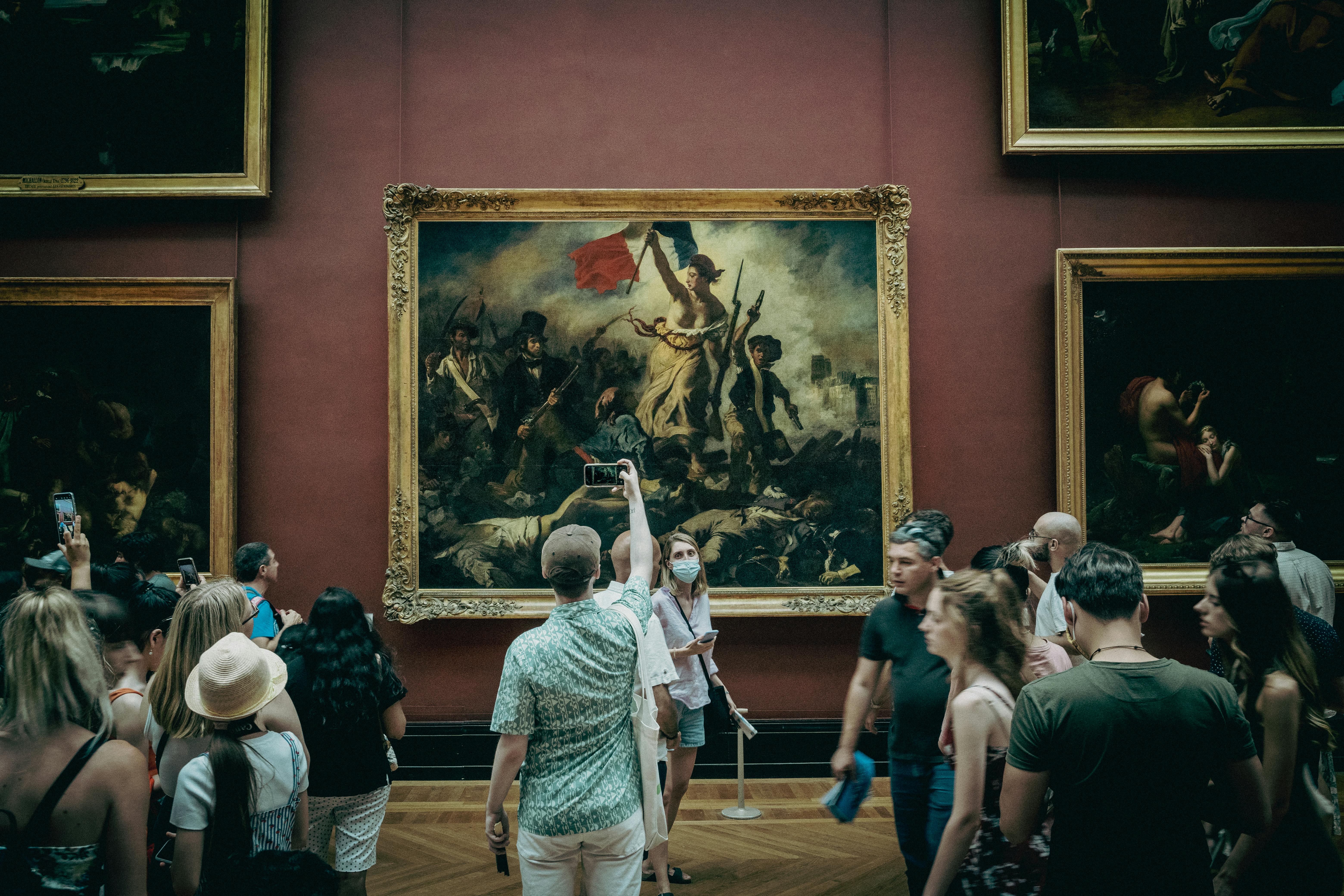 People admiring art at the Louvre Museum, featuring the Mona Lisa and Egyptian antiquities, ideal for exploring art criticism and cultural heritage topics