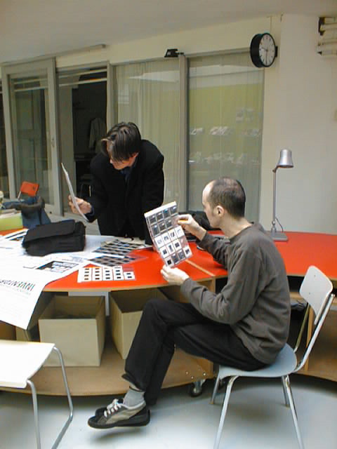 Two individuals examining packaged art samples in an archival setting during a curatorial review in 2000