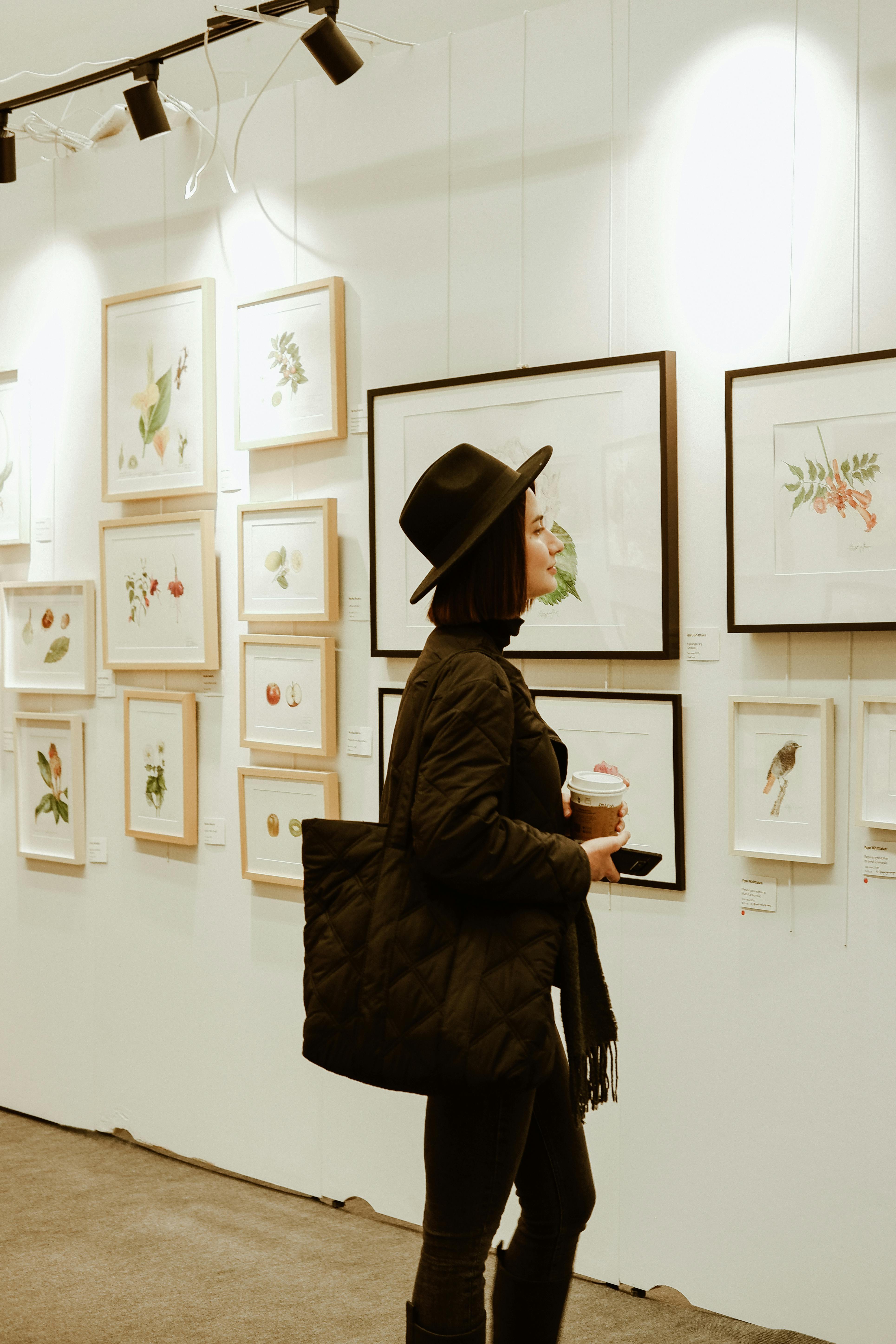 A woman examining paintings in a museum gallery. Image for critical art reception projects. Woman looking at art problem free photo.