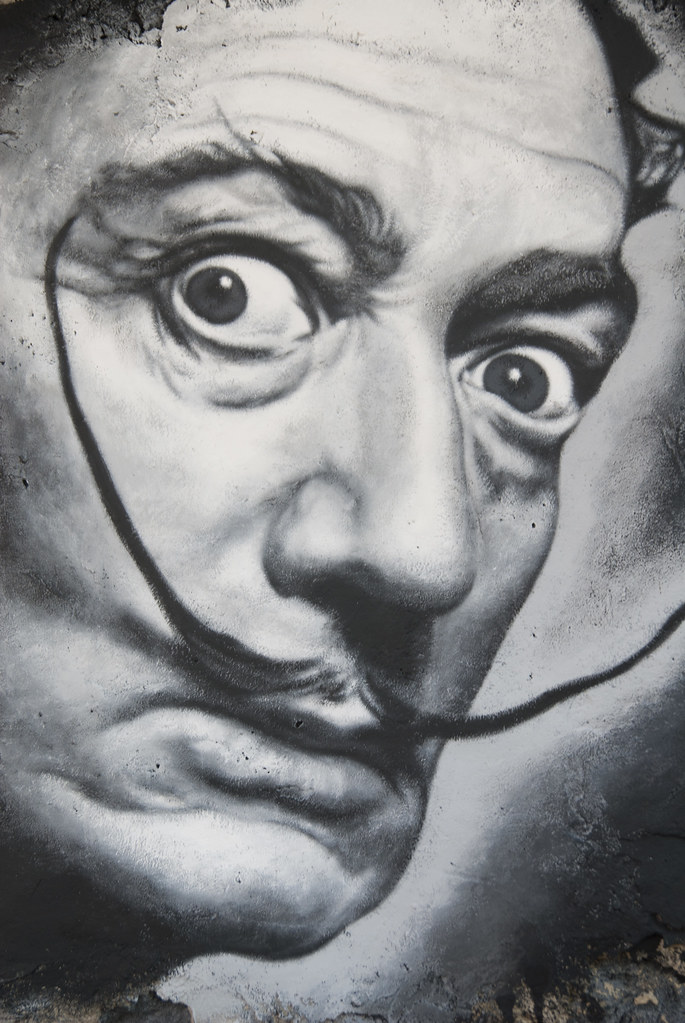 Graffiti portrait of the surrealist artist Salvador Dalí with his signature mustache and intense gaze.