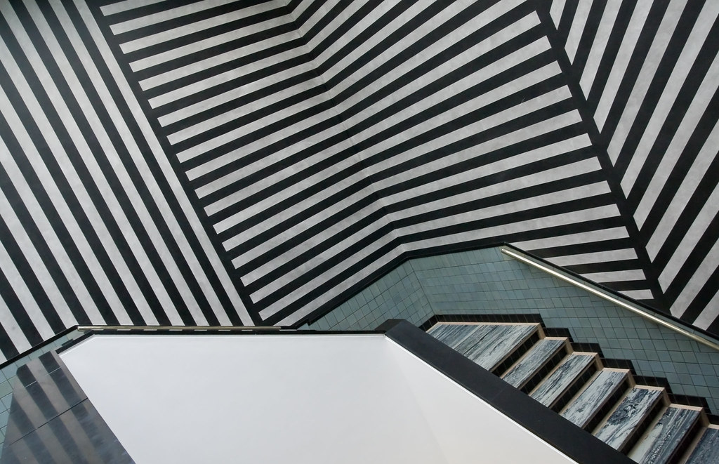 Sol LeWitt's 'Stairs and Stripes' installation at Gemeentemuseum Den Haag. A staircase viewed from above with black and white striped walls and meta-blue marble steps.