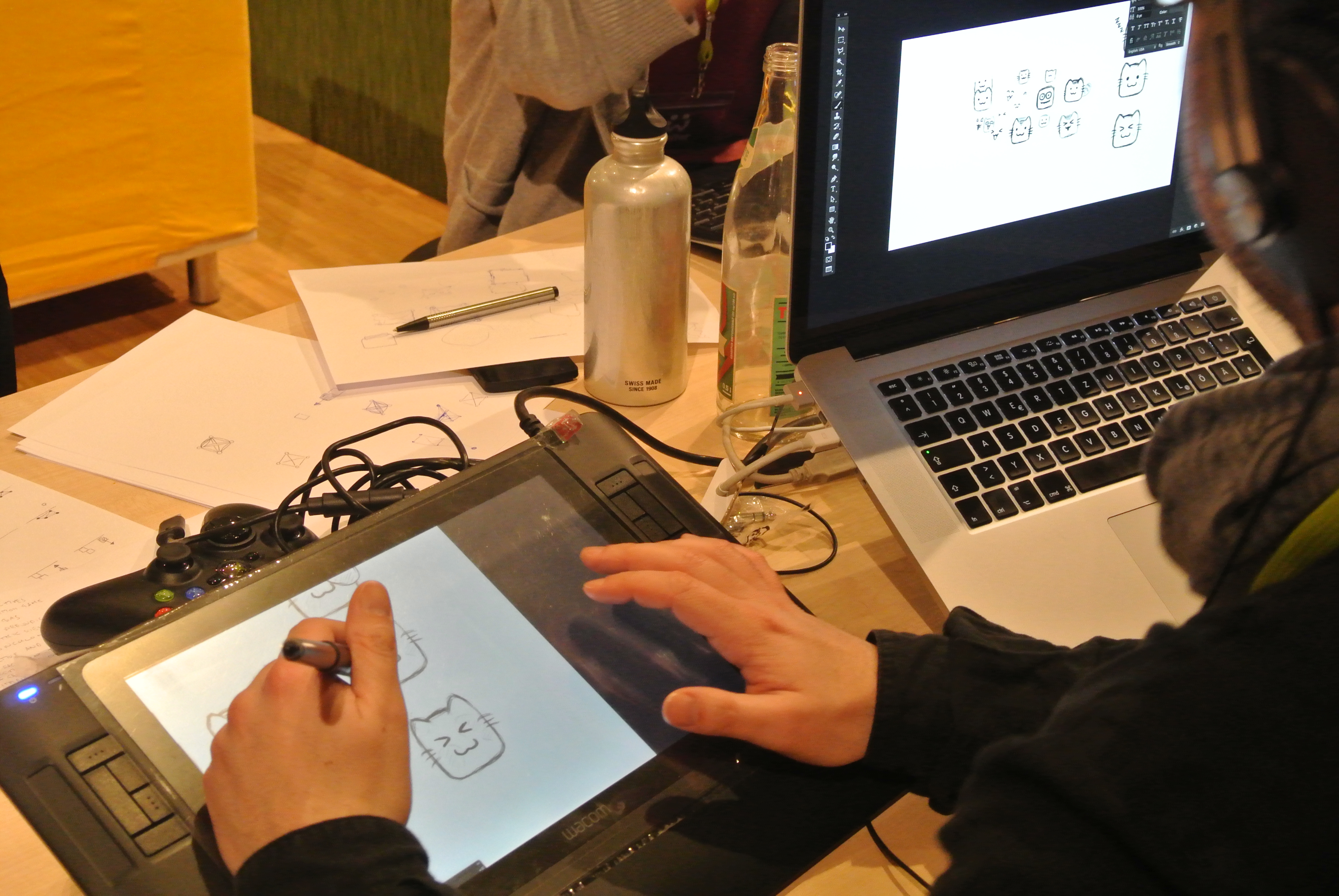 Drawing cats on a Wacom Intuos3 A5 graphics tablet connected to a laptop, with a pen and a water bottle nearby.