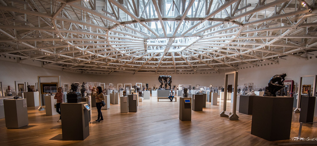 Interior view of Museo Soumaya in Mexico City, showcasing a collection of sculptures under a large, modern, domed ceiling with intricate white metalwork.
