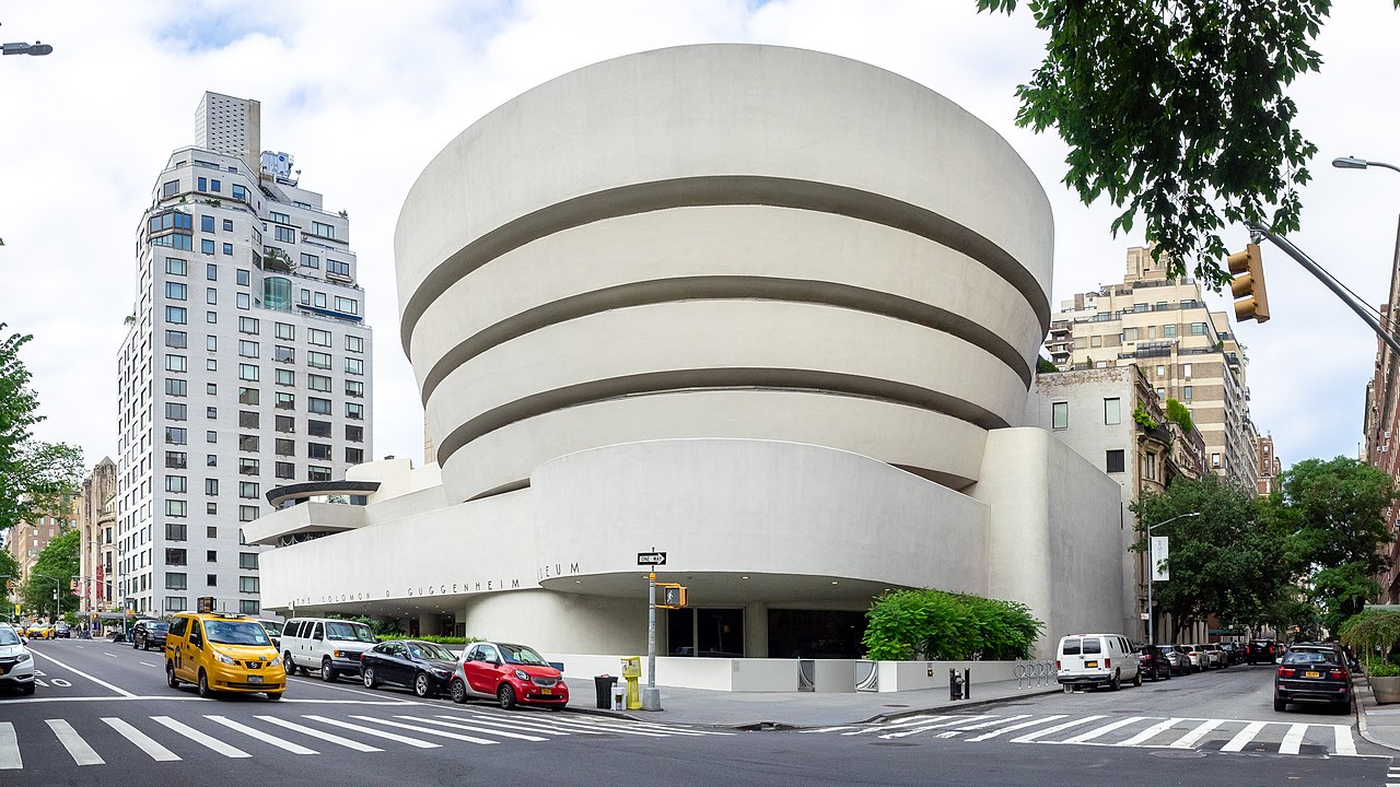 Street corner view of the Solomon R. Guggenheim Museum in New York City, showcasing its distinctive cylindrical architecture.